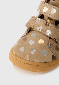 Helle Wildleder-Schuhe mit Klettverschlüssen, verziert mit metallischen Herzmustern in Gold, Silber und Bronze. Gummisohle mit rutschfesten Details.