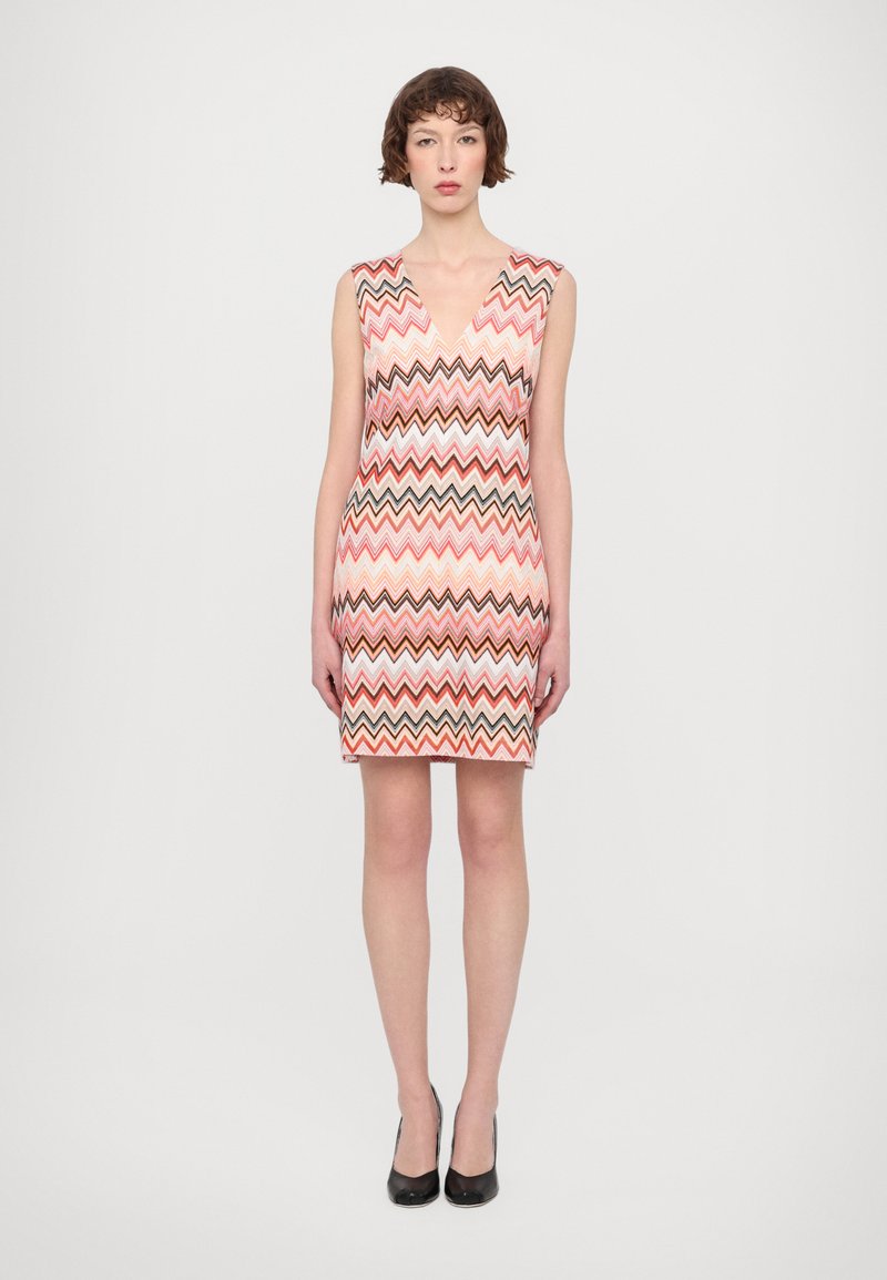 Sleeveless dress with a V-neck, featuring a multicolored zigzag pattern in shades of pink, brown, and cream. Fitted silhouette.