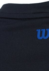 Camisa deportiva azul marino con cuello acanalado y tejido texturizado, con un llamativo logo azul en la parte frontal.