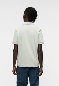 Ανοιχτό γκρι πόλο μπλούζα με κοντά μανίκια και γιακά, με απλή υφή και διακριτικές ριμπ λεπτομέρειες στα μανίκια και τον γιακά.