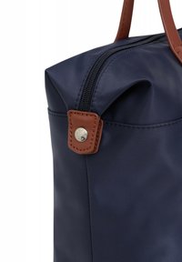 Borsa in nylon blu navy con manico in pelle marrone. Caratterizzata da una chiusura a zip e un dettaglio in pelle con un bottone metallico sul lato.