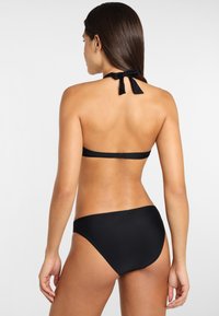Schwarzes Bikini-Set mit Halterhalsband und Rückenverschluss, das eine glatte Textur und ein minimalistisches Design aufweist. Enthält passende Hipster-Unterteile.