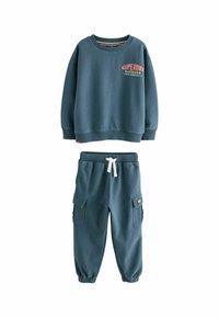 Felpa blu per bambini con la scritta "Superdry Outdoor" abbinata a pantaloni jogger in stile cargo con stringa bianca.