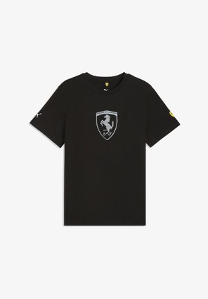 T-shirt nera a maniche corte con logo Ferrari a scudetto color argento al centro, logo Puma bianco sulla manica destra e patch Ferrari giallo sulla manica sinistra.