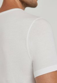 White short-sleeve shirt, made of soft, lightweight fabric. Features a crew neck and subtle texture without visible patterns or embellishments.