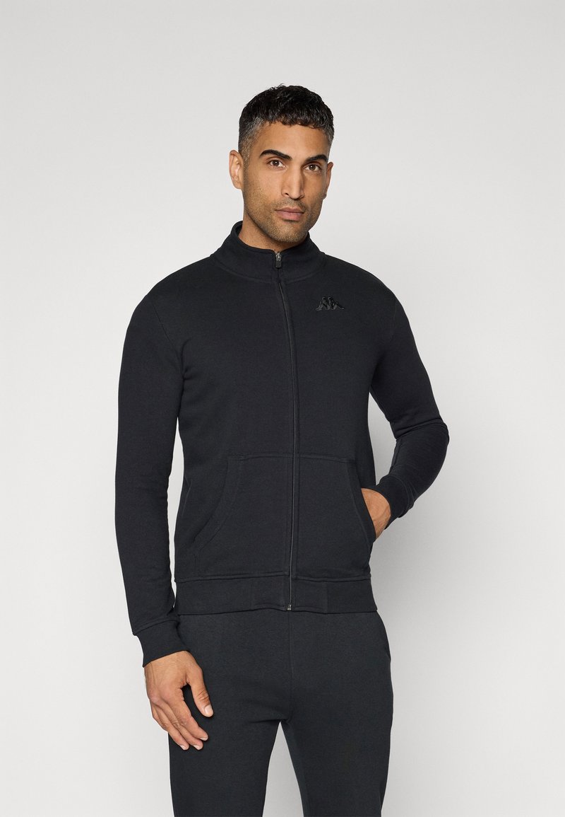 Sweatshirt preto com fecho, feito de um tecido macio, apresenta um gola alta, dois bolsos frontais e um pequeno logótipo no peito.