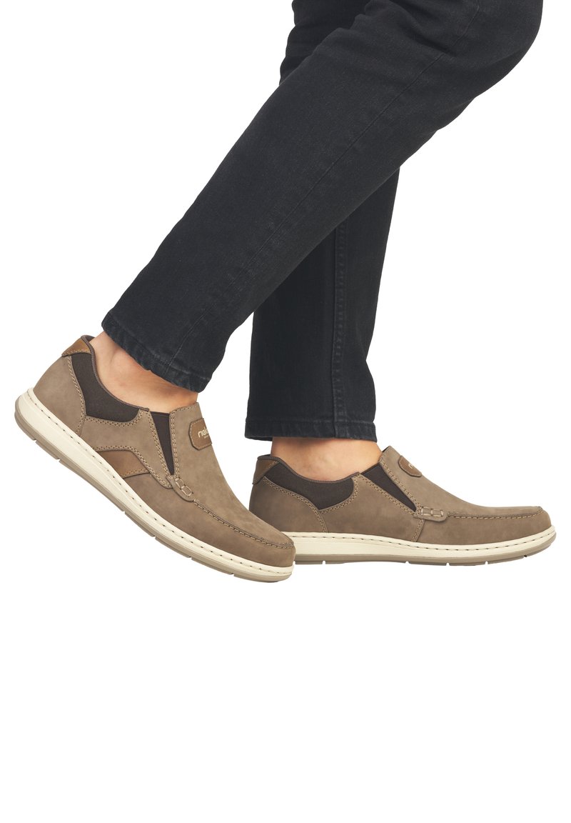 Bruine suède instappers met elastische zijkanten en beige rubberen zolen, met stiksels en een klein logo op de bovenkant.
