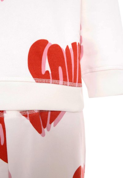 Set di abbigliamento casual in cotone con una base bianca e grandi stampe di cuori rossi e rosa, polsini elasticizzati e una vita a coste per il massimo comfort.