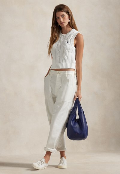 Balts bezroku kabeļadījuma tops, bēšas platām kājām bikses un balti sneakeri. Rokās zila ādas somiņa hobos stils. Vienkāršs, teksturēts un ikdienišķs izskats.