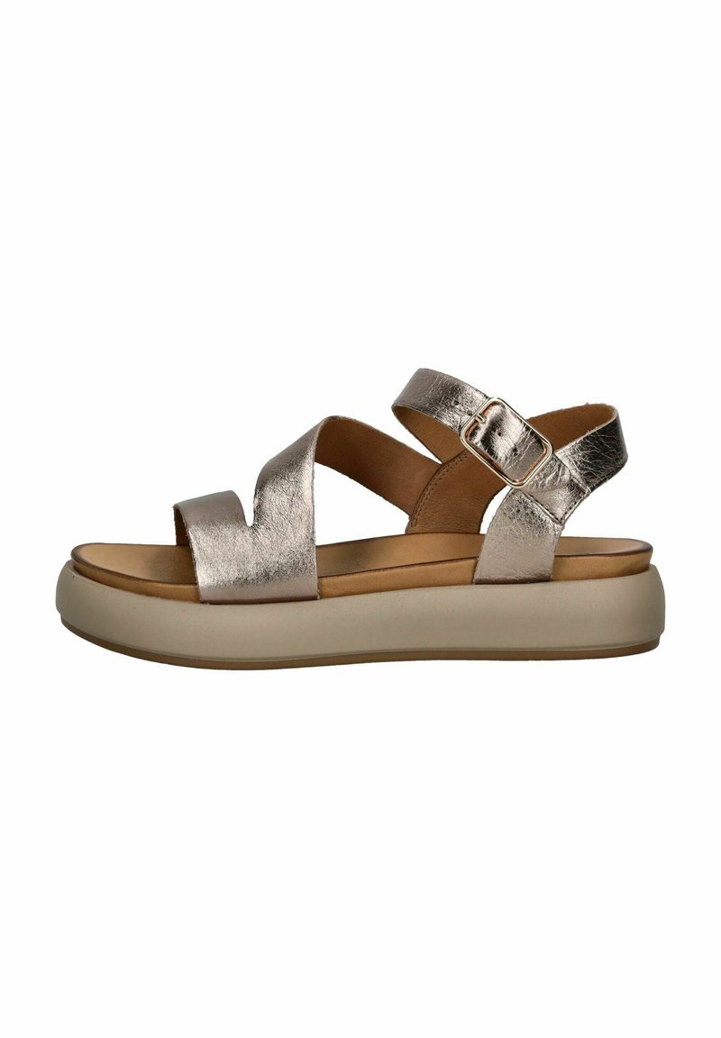 Metalen zilveren sandaal met kruisbanden, verstelbare gespsluiting en een contrasterende beige zool. Zachte leren bovenkant en een gevoerd voetbed.