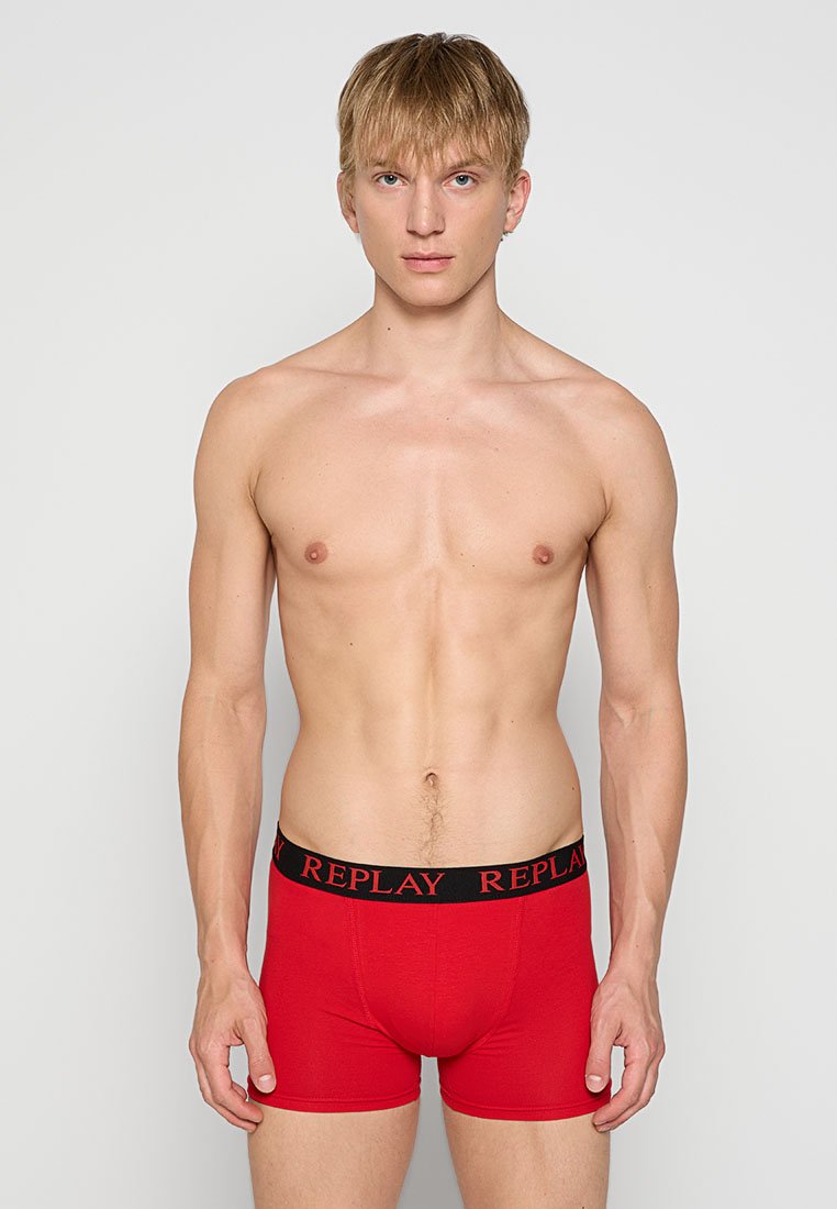 Rote Baumwoll-Boxershorts mit einfarbigem Design, ausgestattet mit einem schwarzen elastischen Bund, der mit rotem Text "REPLAY" beschriftet ist. Glatte Textur, enganliegende Passform.