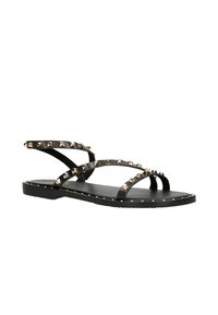 Schwarze Sandalen mit mehreren Riemen und metallicfarbenen Nieten an der Oberseite. Flache Sohle und minimalistisches Design. Glatte Textur und robuste Verarbeitung.