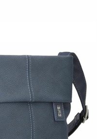 Borsa in pelle blu navy con finitura texturizzata, design pieghevole, tracolla regolabile e un'etichetta logo sul lato. Stile minimalista.