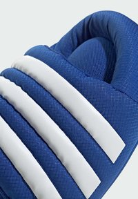 Blauer Sportschuh mit gepolstertem Kragen, weißen Streifen, strukturiertem Stoff und Netzelementen, der eine konturierte Form aufweist.