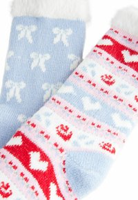 Calcetines acogedores con patrones azules y rojos, que incluyen lazos y corazones. Tejido suave con un detalle de puño blanco esponjoso para mayor calidez.