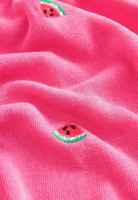 Tejido de punto rosa con motivos de sandía bordados en rojo, verde y negro, creando una textura y diseño juguetones.