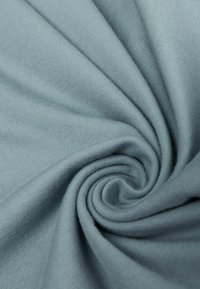 Světle modrá tkanina zkroucená do spirály, která předvádí hladkou texturu s jemným žebrováním a měkkým matným povrchem.