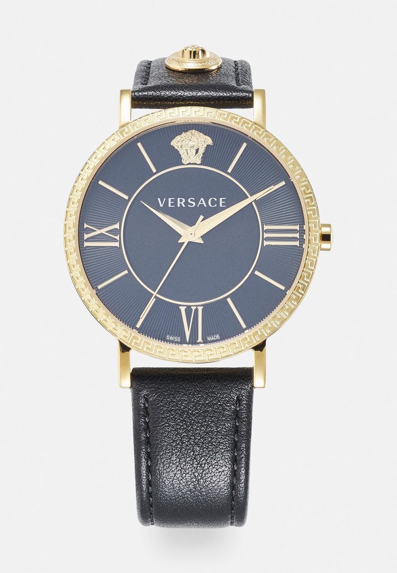Black leather strap watch with a gold-tone round case, navy dial, gold Roman numerals, and a Medusa logo at the top.