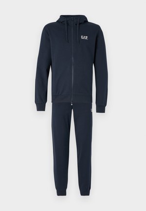 Fato de treino azul-marinho com uma jaqueta com capuz e fecho de correr, e calças combinando. Feito de material macio, apresenta punhos canelados e um logótipo no peito.