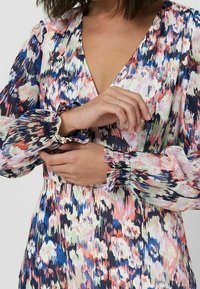 Multicolored floral dress with a deep V-neck, long puff sleeves, and gathered cuffs, featuring a lightweight, textured fabric.
