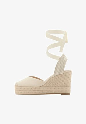 Chaussure espadrille beige à talon compensé avec bout fermé, semelle plateforme en jute tressé, et rubans à nouer autour de la cheville.