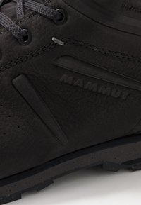 Schwarzer Leder-Wanderschuh mit strukturiertem Obermaterial, verstärkter Zehenkappe, Gummisohle und geprägtem "MAMMUT"-Logo. Ausgestattet mit strapazierfähigen Schnürsenkeln und Ösen.