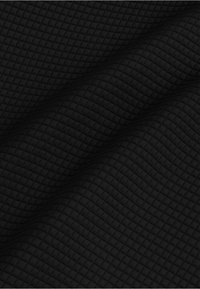 Gestructureerde zwarte stof met een gequilt patroon, dat een reeks kleine, verhoogde vierkanten over het oppervlak toont.