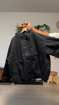 Giubbotto nero stile bomber con collo alto, due tasche anteriori, polsini elasticizzati e vestibilità ampia. Realizzato in tessuto liscio e resistente.