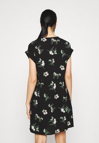 Musta mekko, jossa on kukka- ja perhoskuvio, lyhyet hihat ja rento malli. Pehmeä kangas, jossa on virtaava muotoilu.