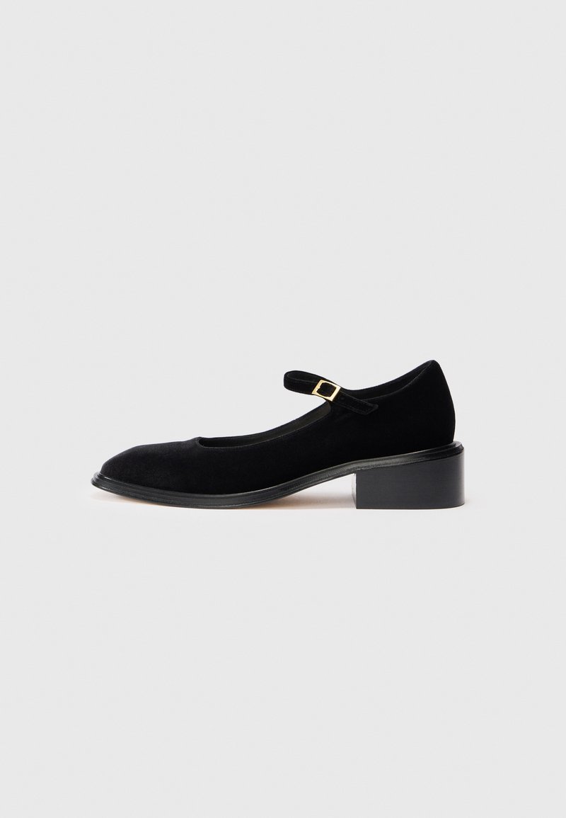 Pantofii negri din suede, stil Mary Jane, cu vârful rotunjit, un mic toc pătrat și o curea cu o cataramă aurie. Textură netedă.