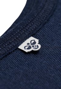 Marinblått tyg med en strukturerad yta har en etikett med en logotyp och mönster. U-ringningen är ribbad och väl sydd.