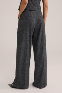 Lahtised püksid tumedas hallis kangas, millel on peen tekstuur, kõrge vöökoht ja küljetaskud. Kaunistatud peente valgete laikudega.