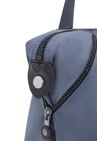 Borsa in nylon blu con cerniera nera e dettaglio in pelle, caratterizzata da un bottone con logo argentato e tessuto testurizzato, progettata per resistenza e utilità.
