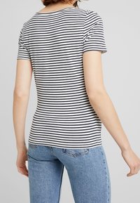 T-shirt rayé blanc et marine, manches courtes, encolure ronde, coupe slim. Tissu doux en mélange de coton avec une texture lisse.