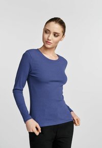 Rybkowany top z długim rękawem w głębokim niebieskim kolorze, z okrągłym dekoltem i dopasowanym krojem. Gładki materiał o subtelnej teksturze i elastyczności.