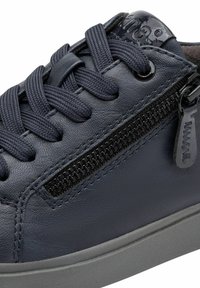 Navy blue leather sneaker with thick navy laces, side zipper, stitched details, and grey rubber sole.