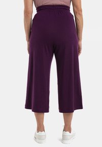 Lila, vida culotter med elastisk midjeband. Tillverkade av mjukt tyg med en slät yta, i midikjollängd.