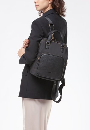 Zaino nero con tasca frontale in pelle texturizzata, hardware dorato, doppi manici superiori e tracolla regolabile. Corpo in tessuto liscio.
