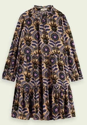 Enfant portant une robe fleurie à manches longues, longueur genou avec un fond beige, associée à des chaussettes claires et des mocassins noirs.