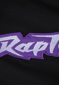 Il tessuto nero presenta un logo ricamato viola con un carattere audace. La texture è liscia e il design include spigoli vivi e angolari.