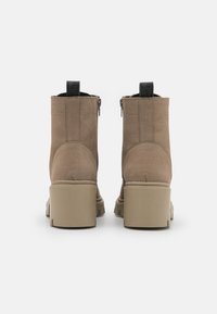 Tan ankle boots with a smooth leather finish, side zippers, and chunky beige soles. Features a pull tab on the back for easy wear.