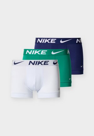 Tre Nike bokserbriefs i hvitt, grønt og marineblått med logo på linningen og liten Swoosh på låret mot ensfarget bakgrunn.