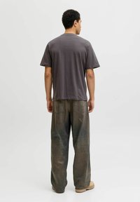 Grå bomulds t-shirt med korte ærmer, parret med løse olivengrønne jeans. Outfitet har et simpelt, afslappet design.
