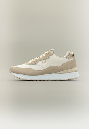 Beżowy i biały sneaker z teksturami z zamszu i skóry, złotym logo „GAP”, białą podeszwą i beżowymi sznurowadłami na neutralnym tle.