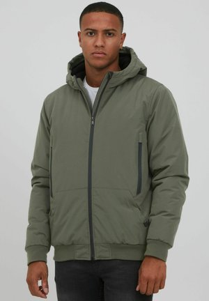 Olive green hooded jacket with a zip front, side pockets, and elastic cuffs. Features a smooth texture and a contrasting black inner lining.