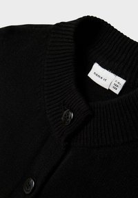 Schwarze Strickjacke mit geripptem Kragen und zwei schwarzen Knöpfen, die das weiße Größenetikett "name it" für 7-8 Jahre zeigt.