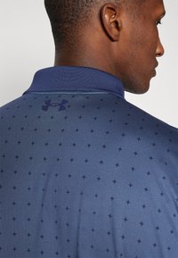 Námořnická polo košile s texturovaným vzorem malých hvězd, s klasickým límečkem a logem Under Armour ve stejné námořnické barvě na zadní straně.