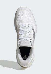 Biały but sportowy z siateczkową cholewką, wzmocnionym noskiem, płaskimi sznurowadłami, wyściełanym kołnierzem i szarymi akcentami po bokach.