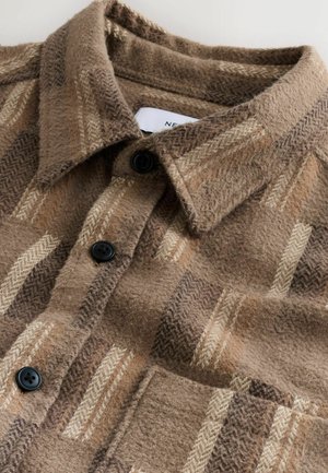 Braun kariertes Hemd aus strukturiertem Stoff. Verfügt über einen umgeschlagenen Kragen, schwarze Knöpfe und vertikale sowie horizontale Streifen in Creme und hellbraun.