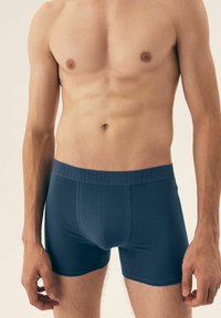 Granatowe slipy męskie z gładkiego materiału, z teksturowanym pasem w talii z wytłoczonym napisem "HENDERSON". Klasyczny krój i prosty design.